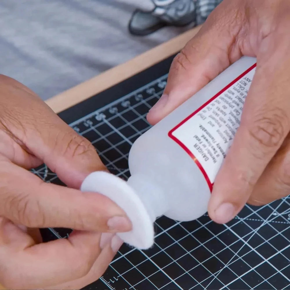 Persoana care tine in mana disc demachiant si degresant piele pe un birou cu cutting mat Angelus