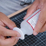 Persoana care tine in mana disc demachiant si degresant piele pe un birou cu cutting mat Angelus